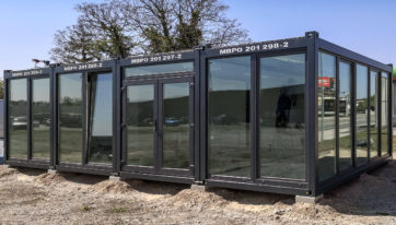 anthrazitfarbene Containeranlage mit verspiegelten Fensterflächen