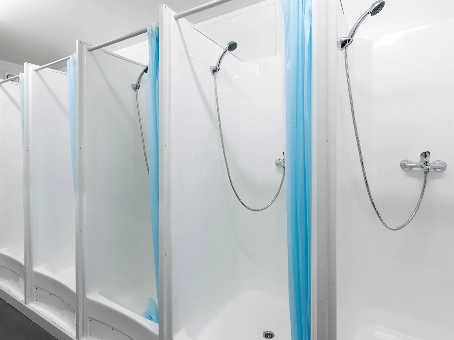 sanitärcontainer als duschcontainer zur miete mit vier duschen samt vorhang und duschbrausen.