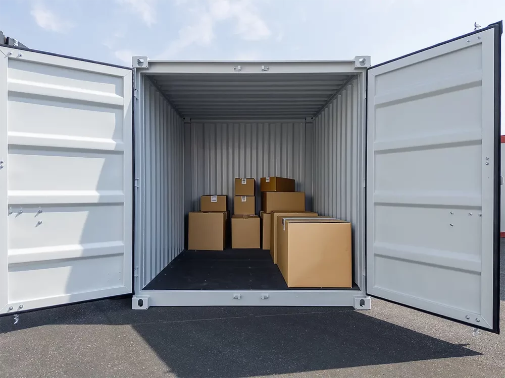 Lagercontainer mit geöffneten Türen und sichtbaren Umzugskartons für die Zwischenlagerung während eines Umbaus eines Betriebs.