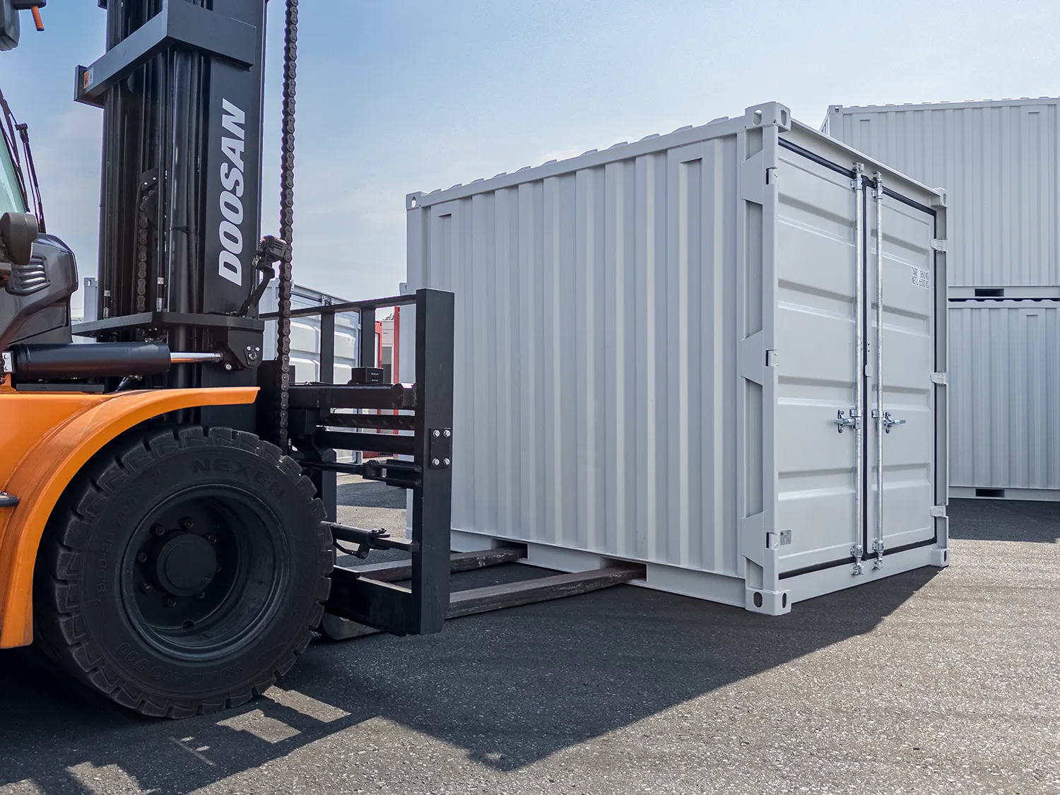 Stapler wie dieser einen Mietcontainer MX10 Lagercontainer mit den Gabeln über die Staplertaschen hebt.